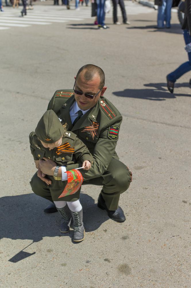 Image from Victory Day in Transnistria -  A military official holds his daughter, who wears army...