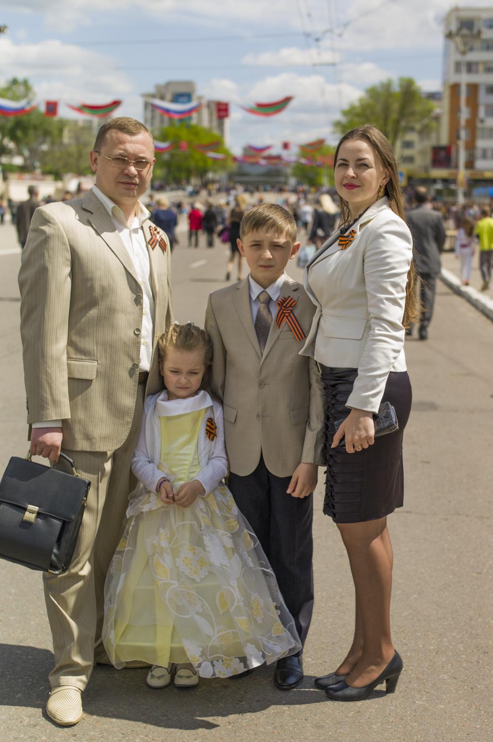  A family dressed for the special occasion stands for a portrait on the main avenue of Tiraspol...