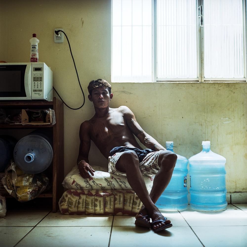 November 28, 2014. A Munduruku youth sits on bags of sugar during an occupation of the FUNAI offices (Brazil's National Indian Foundation) in Itaituba, Para, Brazil. The occupation was in protest to the fact that government has refused to publish official documents that would recognize Munduruku traditional territory. If recognized, flooding of the territory by new hydroelectric development would be illegal under Brazilian Law. Brazil has some of the best environmental and indigenous protection laws in the world, but large scale development such as dams and mines are often decided before environmental reviews have even begin.