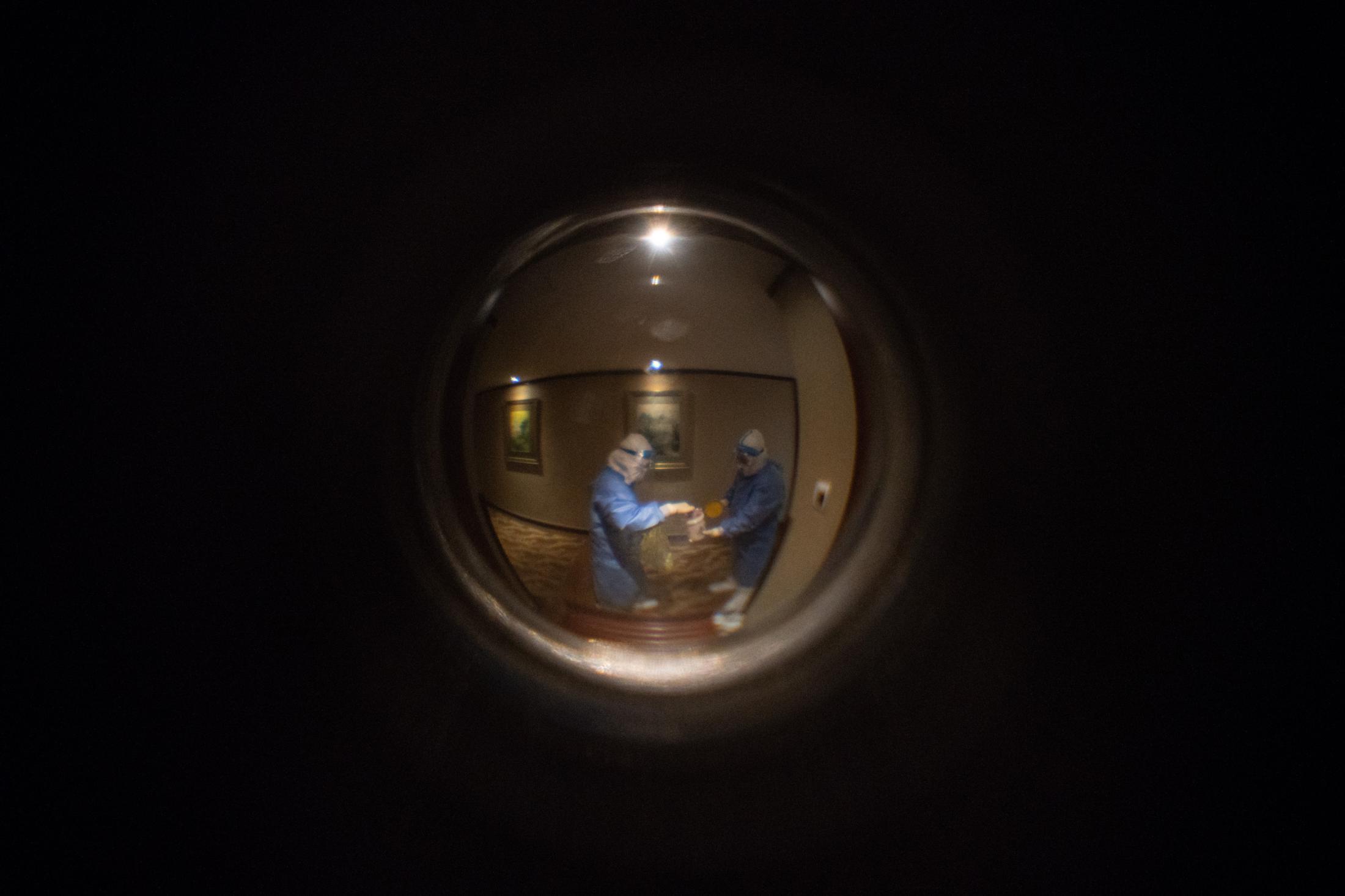 Seen through the peephole: after the COVID-19 test, the two medical workers put my sample into a bag before going to the next room to do the test.