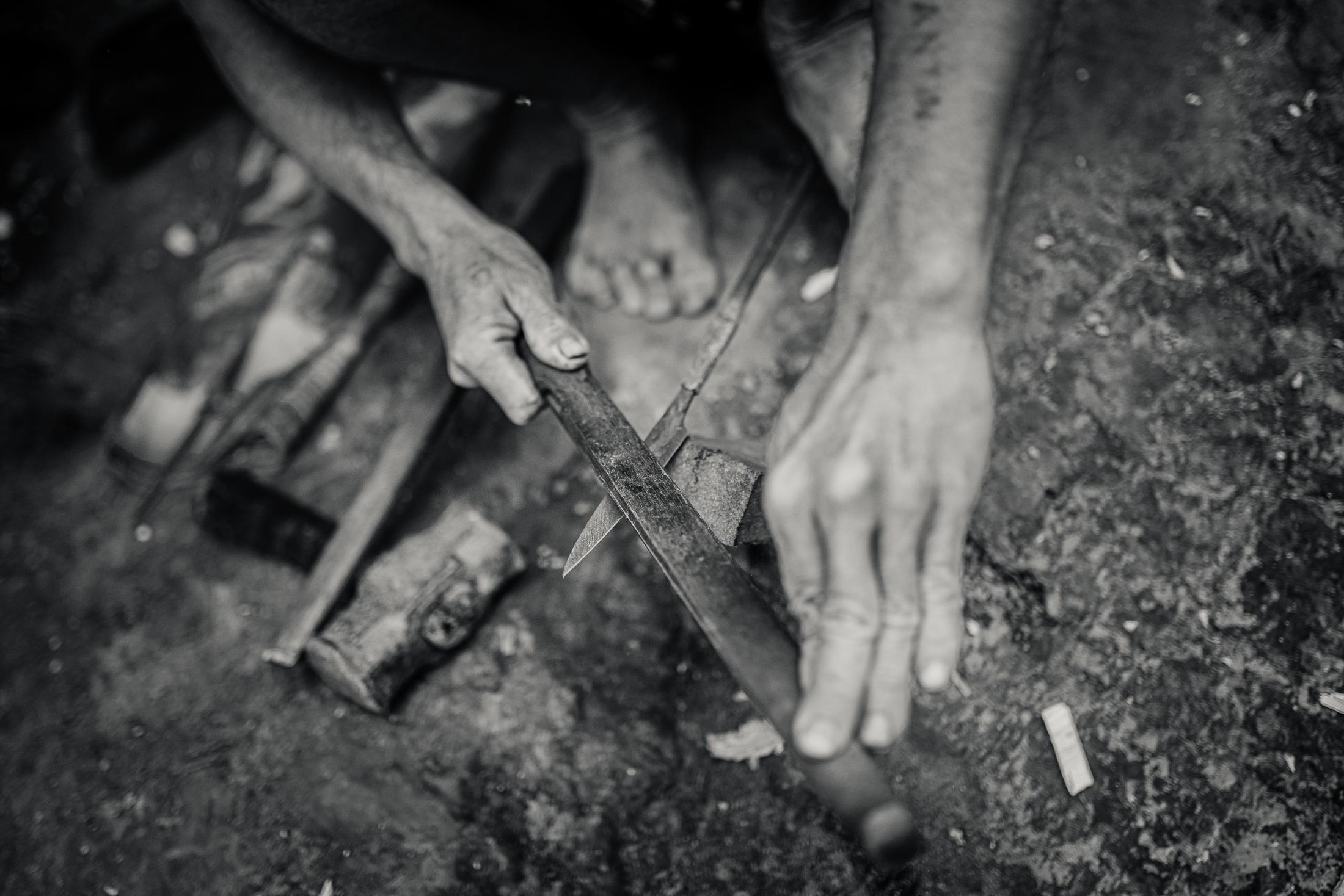 Indigenous Land Rights in Sarawak -  A man works on an edged tool in the Long Beku village...