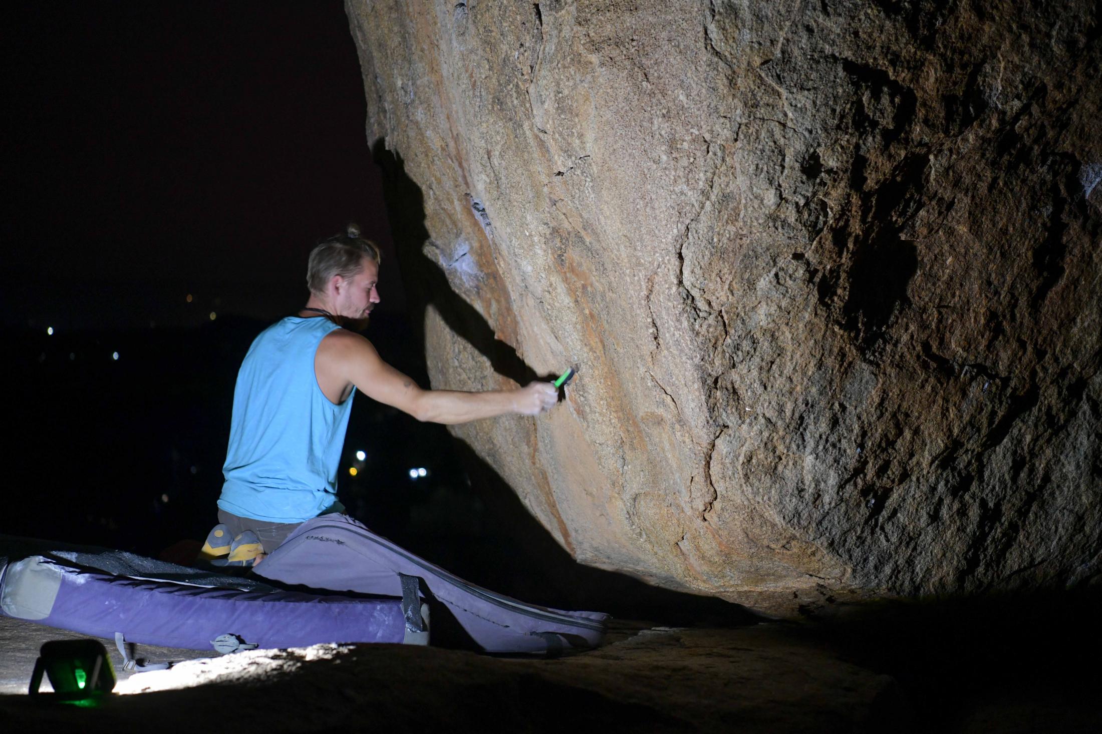 Using a night lamp Mathias brushes the rocks with chalk before the climb