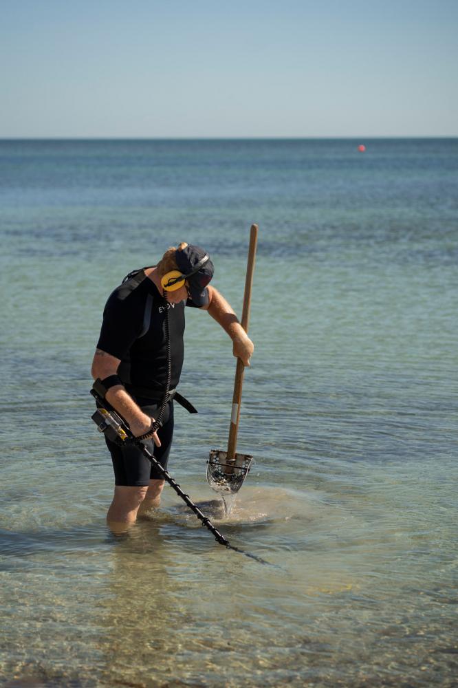 Image from Miami Bites - A man looks for valuables with a metal detector in the...