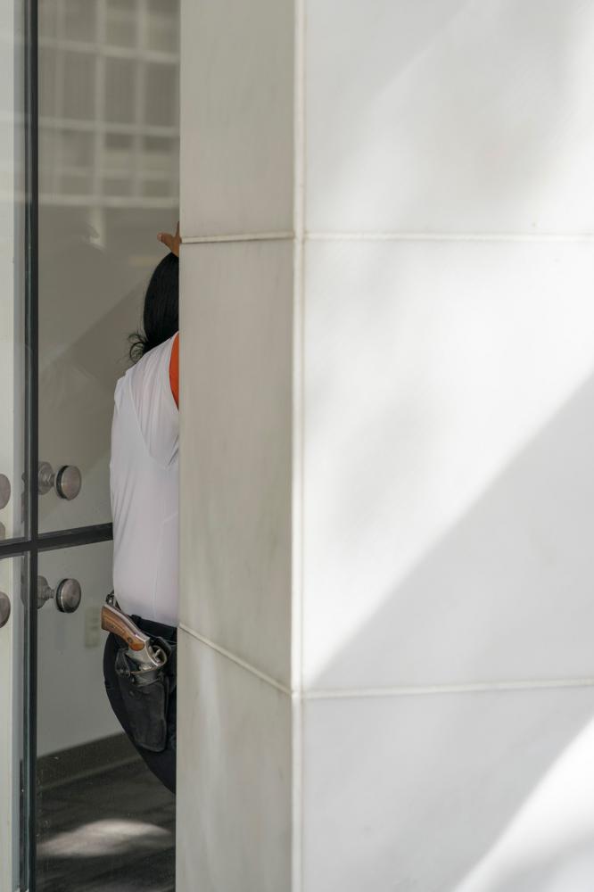 Miami Bites - A security guard leans on the wall of a bank as her gun...