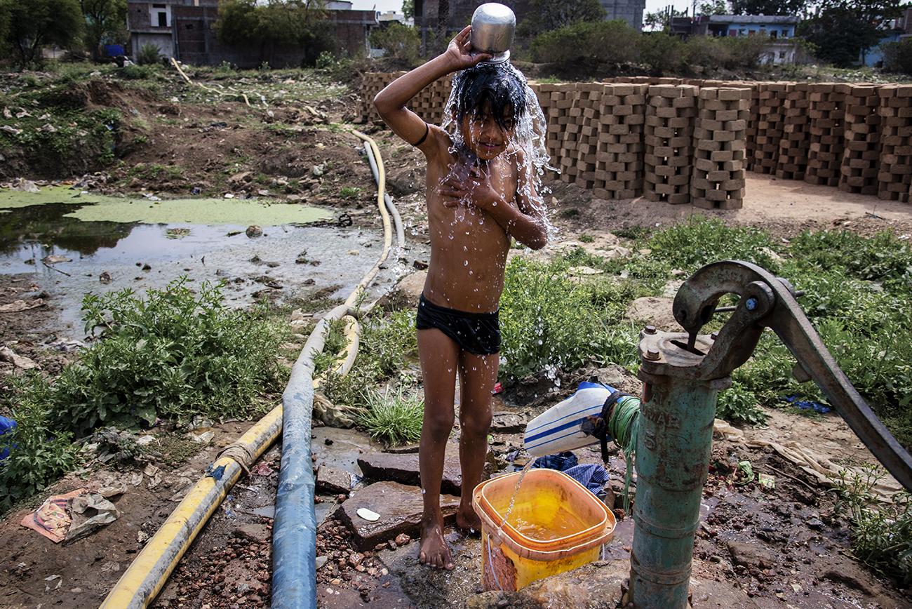 Migrant workers in Bhopal - A brick field worker's child bathing in polluted...