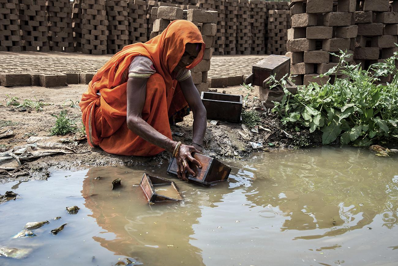 Migrant workers in Bhopal - A brick field worker using polluted water to clean up...