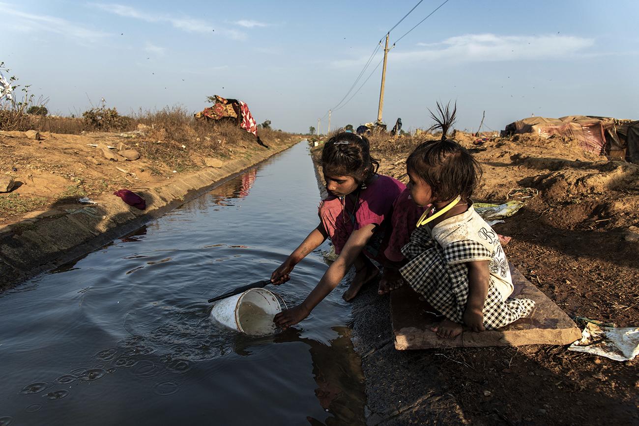 Migrant workers in Bhopal - Migrant children pouring water in a balti near Adnmpur...