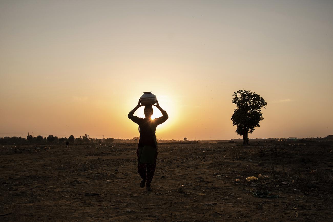 Migrant workers in Bhopal - woman carrying water near Adnmpur during sunset.