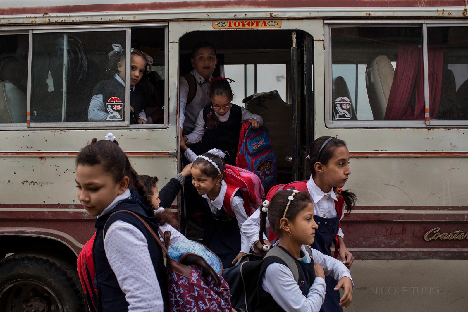 Schoolchildren exit a bus in we...their education. November 2017.