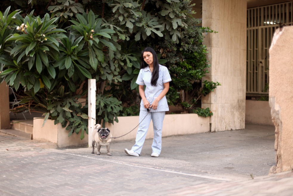 Miles, 25, a migrant domestic worker from the Phillipinnes walks her employer's dog in front of their apartment building in Beirut, Lebanon....