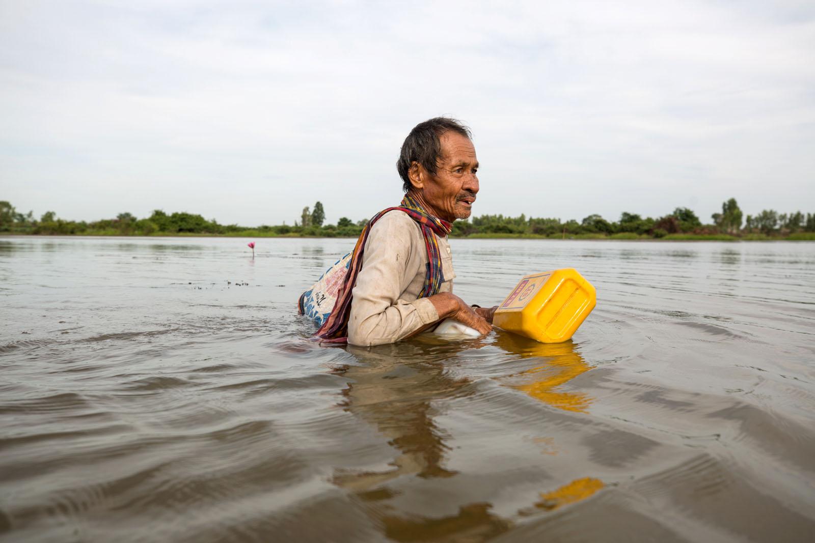 THREE DECADES OF AN ANTI-DAM STRUGGLE - Sombun Suphap, 65, wades through the water of the flooded...