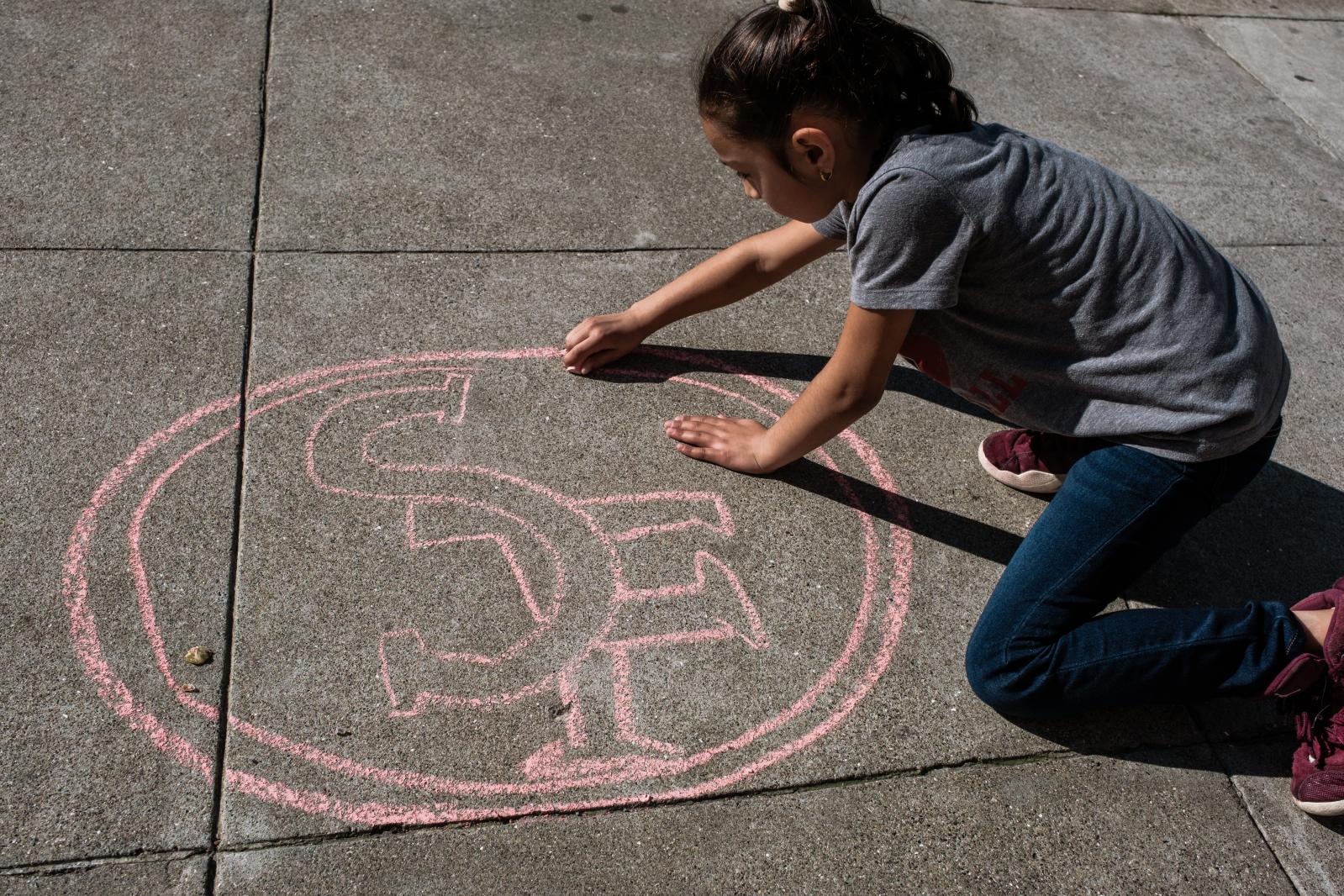 Image from A Scarlet and Gold Neighborhood - Anahai Hernandez, 9, creates a 49er logo on the sidewalk...