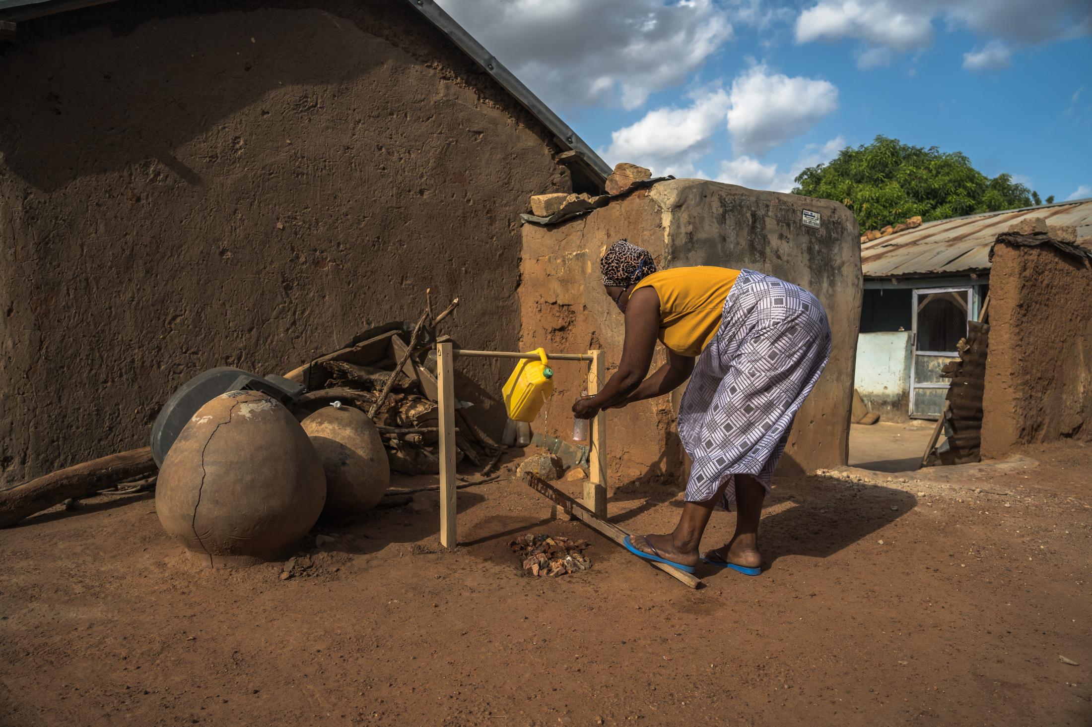 A member of Kperiga community washes her hands using &quot;tippy tap&quot; handwashing system introduced by CRS ICOWASH project during the...