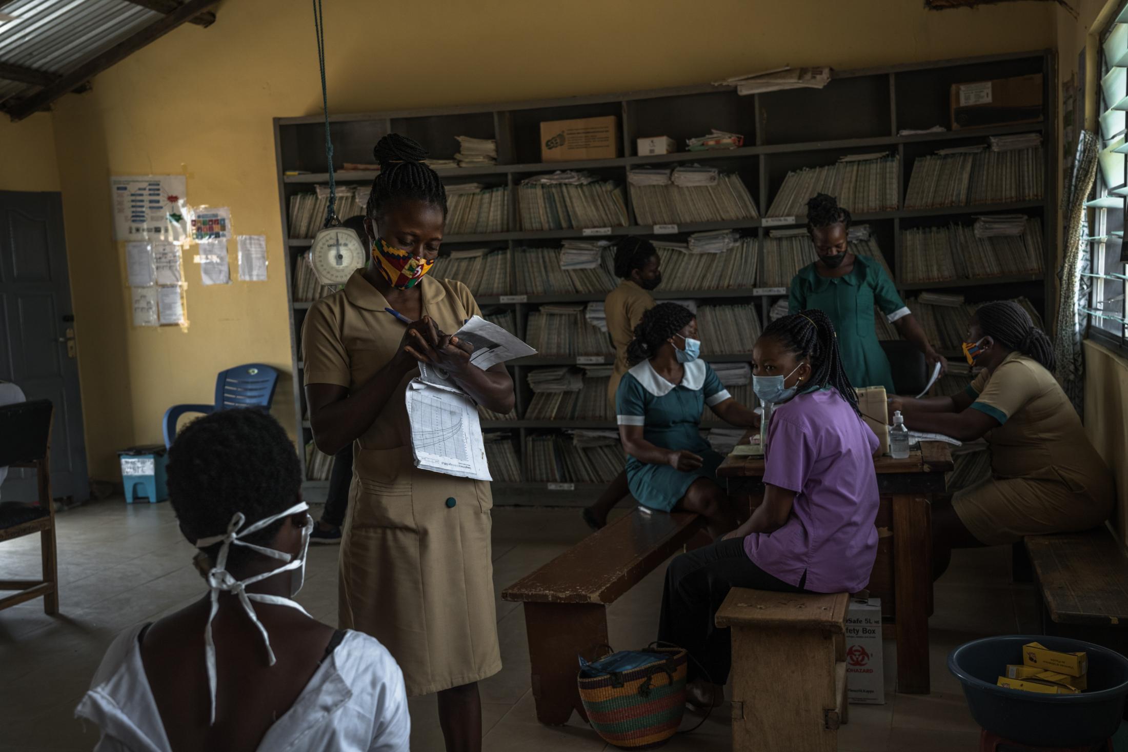 Covid-19 Response in Northern Ghana - Nurse at Wikongo CHPS records information while...