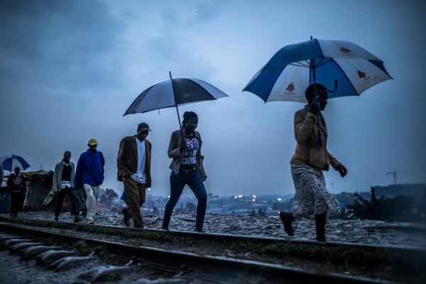 Brian Otieno | Kibera Stories - Residents walk along the muddy rail track in Kibera after...