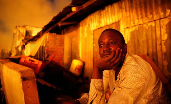 Thomas Mukoya | A Spectacular Failure - A resident watches as houses burn in a fire that broke...