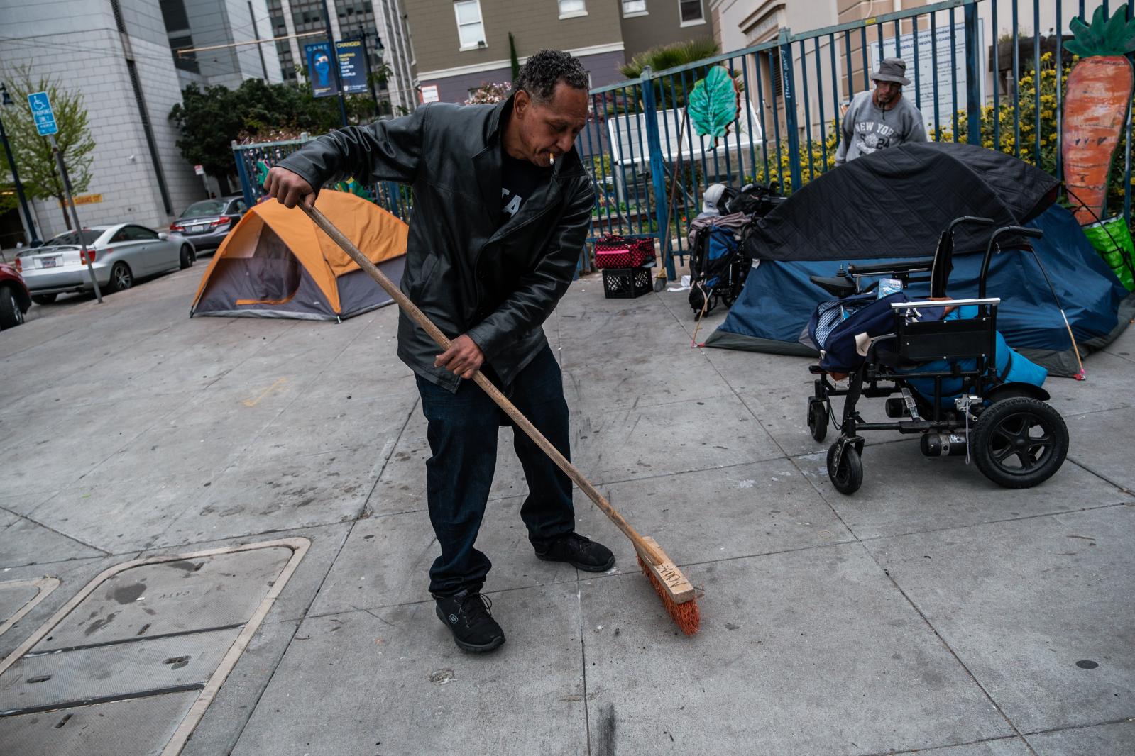 Image from San Francisco's Housing Crisis - Mojo Dumetz, a homeless man, sweeps up the area around...