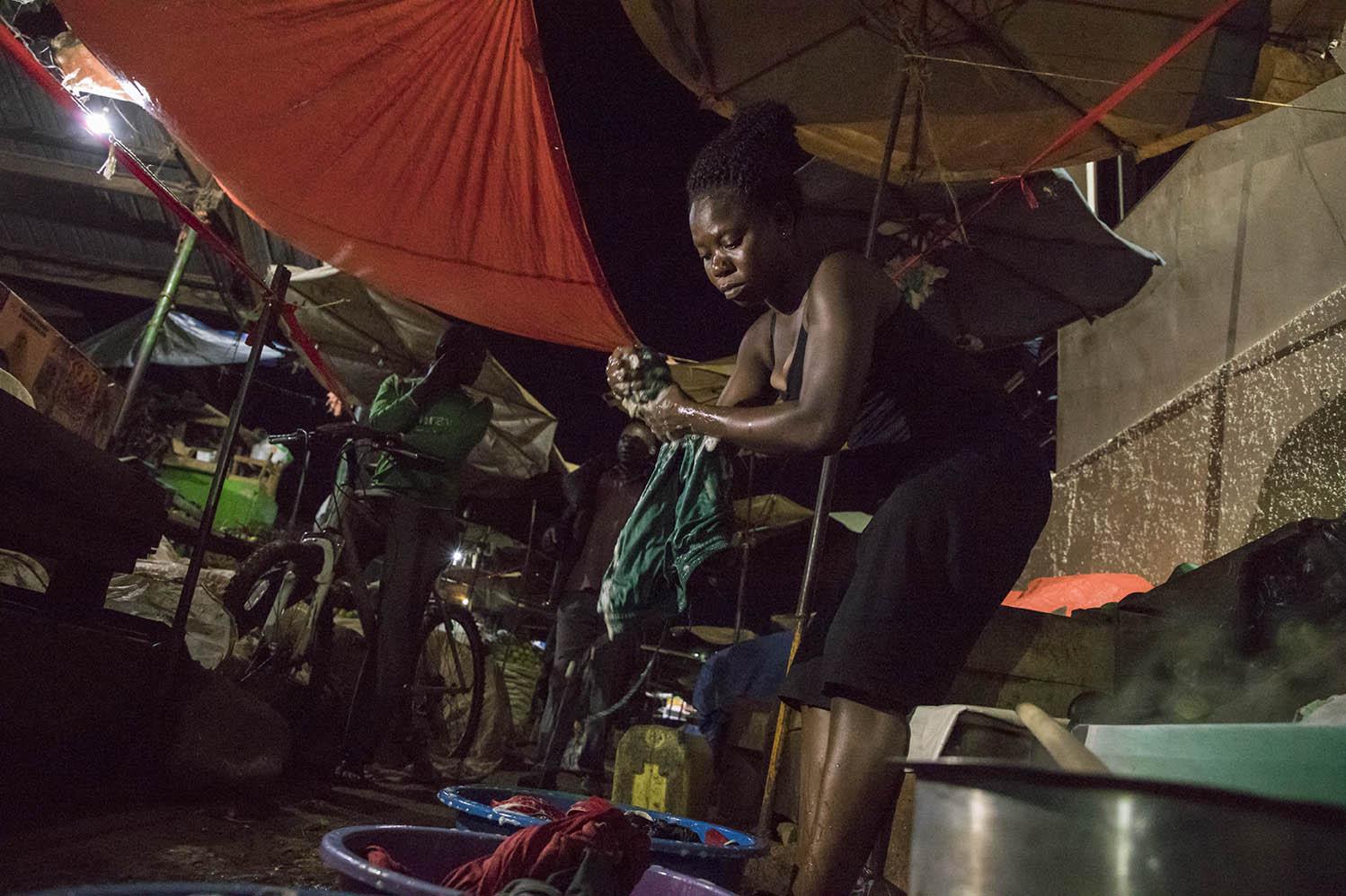A woman washing her clothes along a walkway in the Nakawa Market after spending four days away...