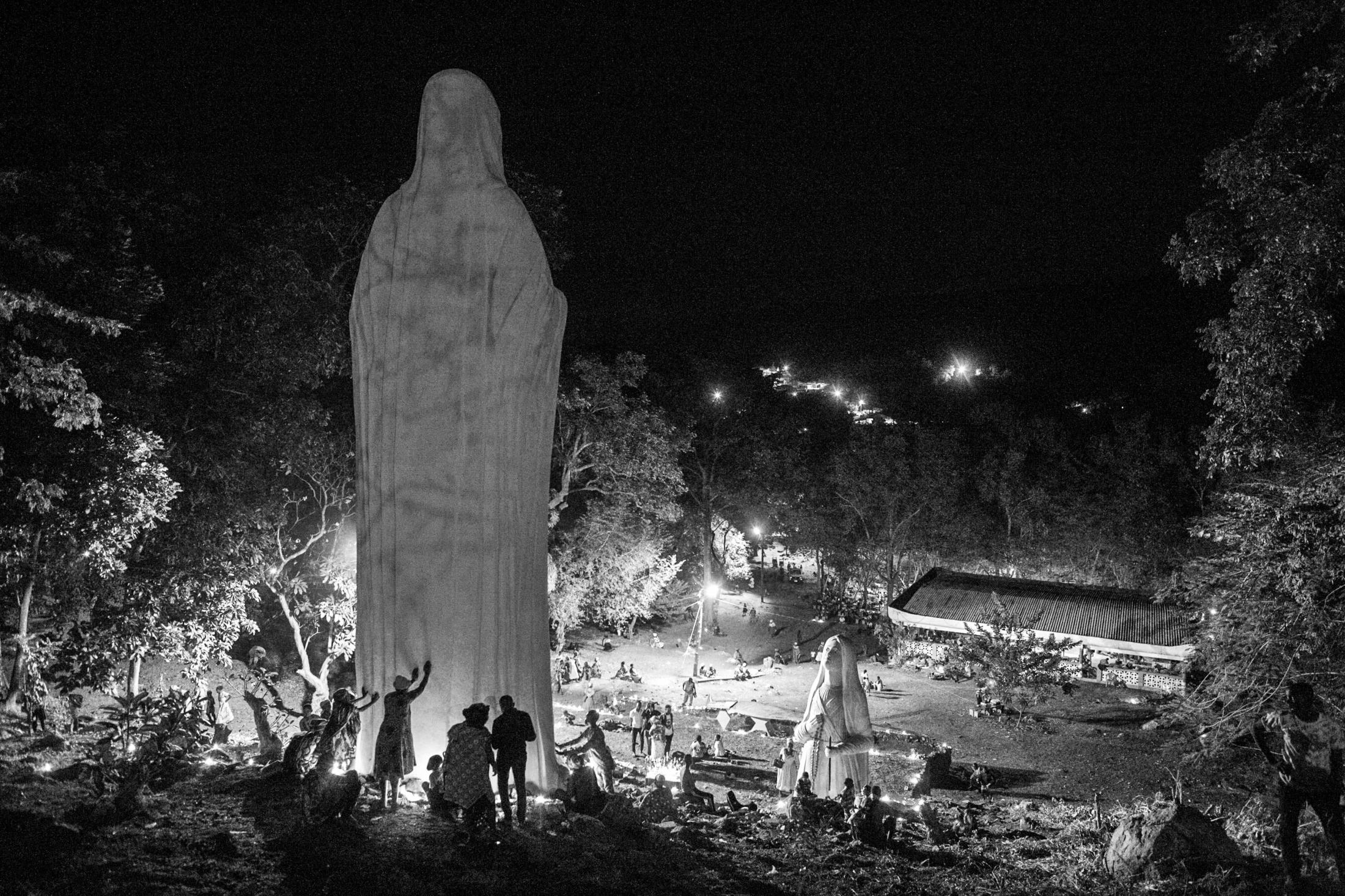 Pilgrims touch a giant statue of Maria to pray, the mother of Jesus the centrepiece of worship at the Our Lady of Lourdes grotto.