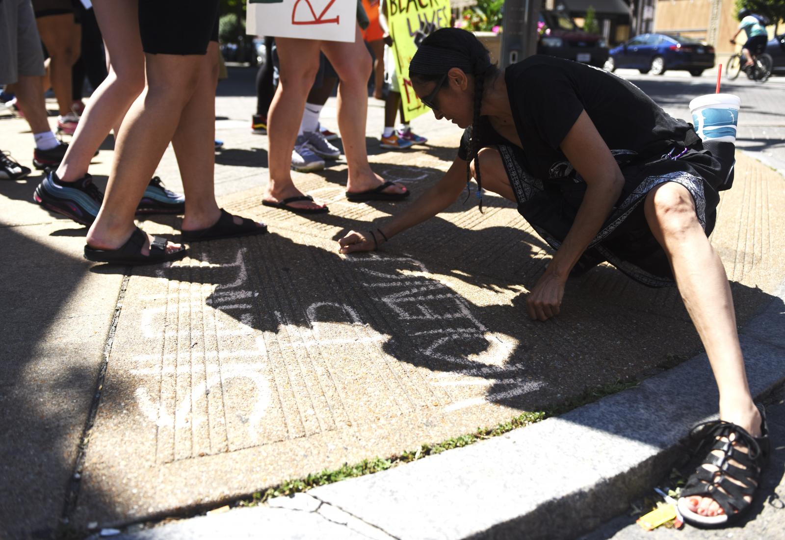 A woman marks the sidewalk with... at protests across the nation.