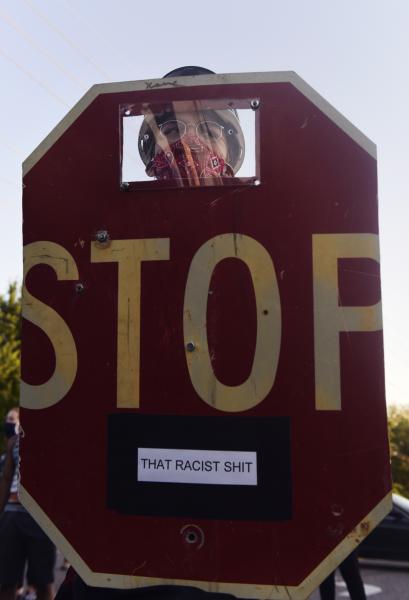 A protestor holds up a shield made out of a stop sign on Sunday, June 7, 2020, in front of the Florissant Police Department.