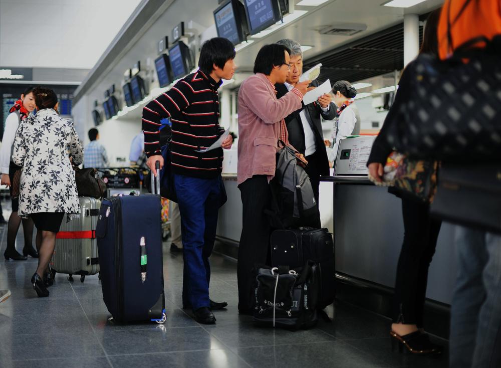 Li Chuan-hua and Su Li-li check their plane ticket to Qingdao Liuting International Airport,...