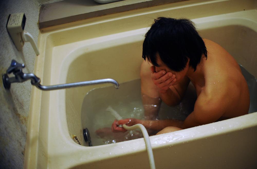 Li Chuan-hua takes a bath after a long day at work on December 2010. He usually takes a shower,...