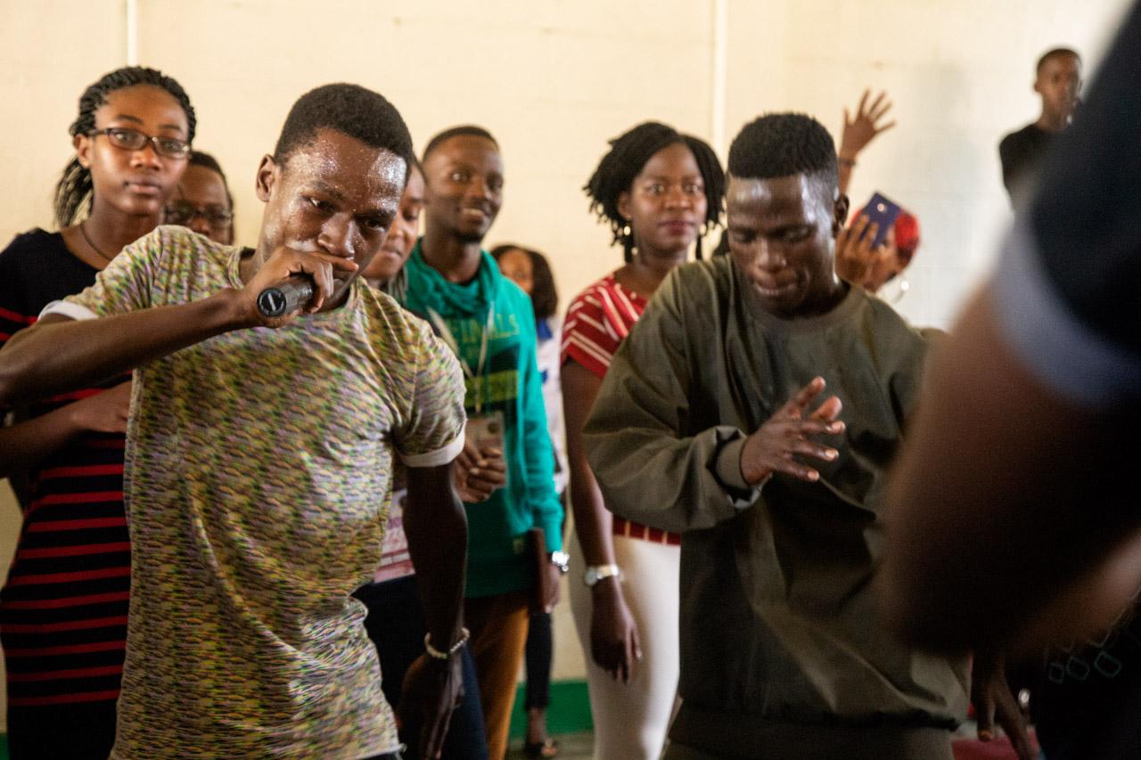 Naxa (holding microphone) leads a MADS hype session at Vienna College, one of the high schools that the youth group visits over the weekends as part of its mission to share music, dance and the gospel. 