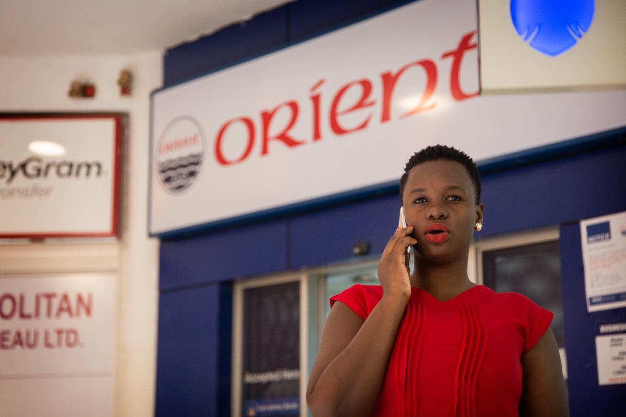 Ritah takes a phone call outside the bank where she works, in Garden City Shopping Mall, Kampala. 