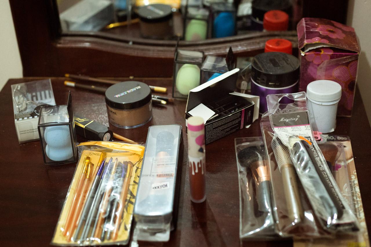 A countertop in Shamim&rsquo;s bedroom, covered with both old and new makeup kits. She has lots of different beauty products scattered all around the room, testament to her dedication to the job.