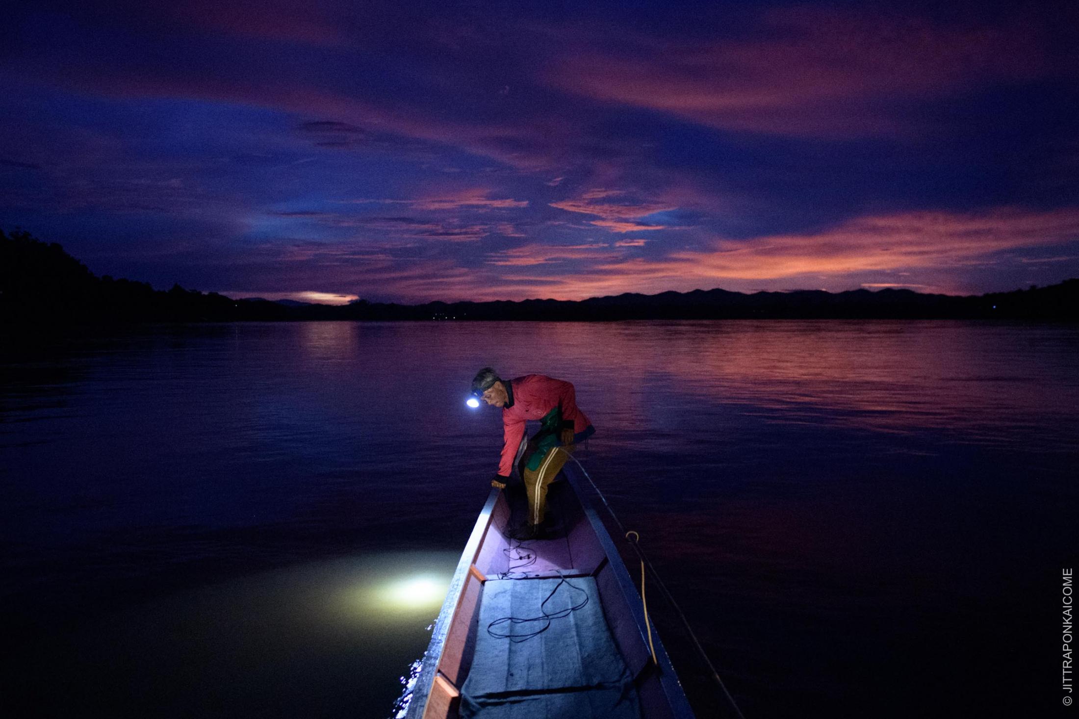 At dusk, a fisherman checks his net. Chiang Khan is close to the location of the Sanakham Dam plan. Here too, the riverine ecosystem is seriously disturbed, resulting in fewer fish in the river; caused by the Xayaburi Dam and other dams upstream. In Loei, Thailand &ndash; August 2020.