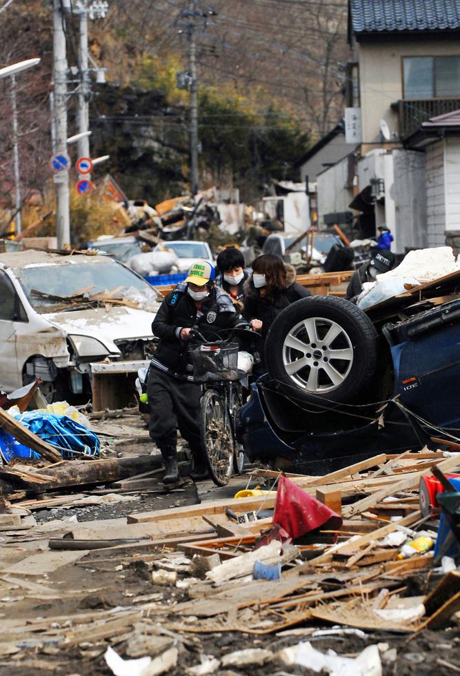 Residents push a bicycle in the rubble and ruins of the earthquake and tsunami.There was...
