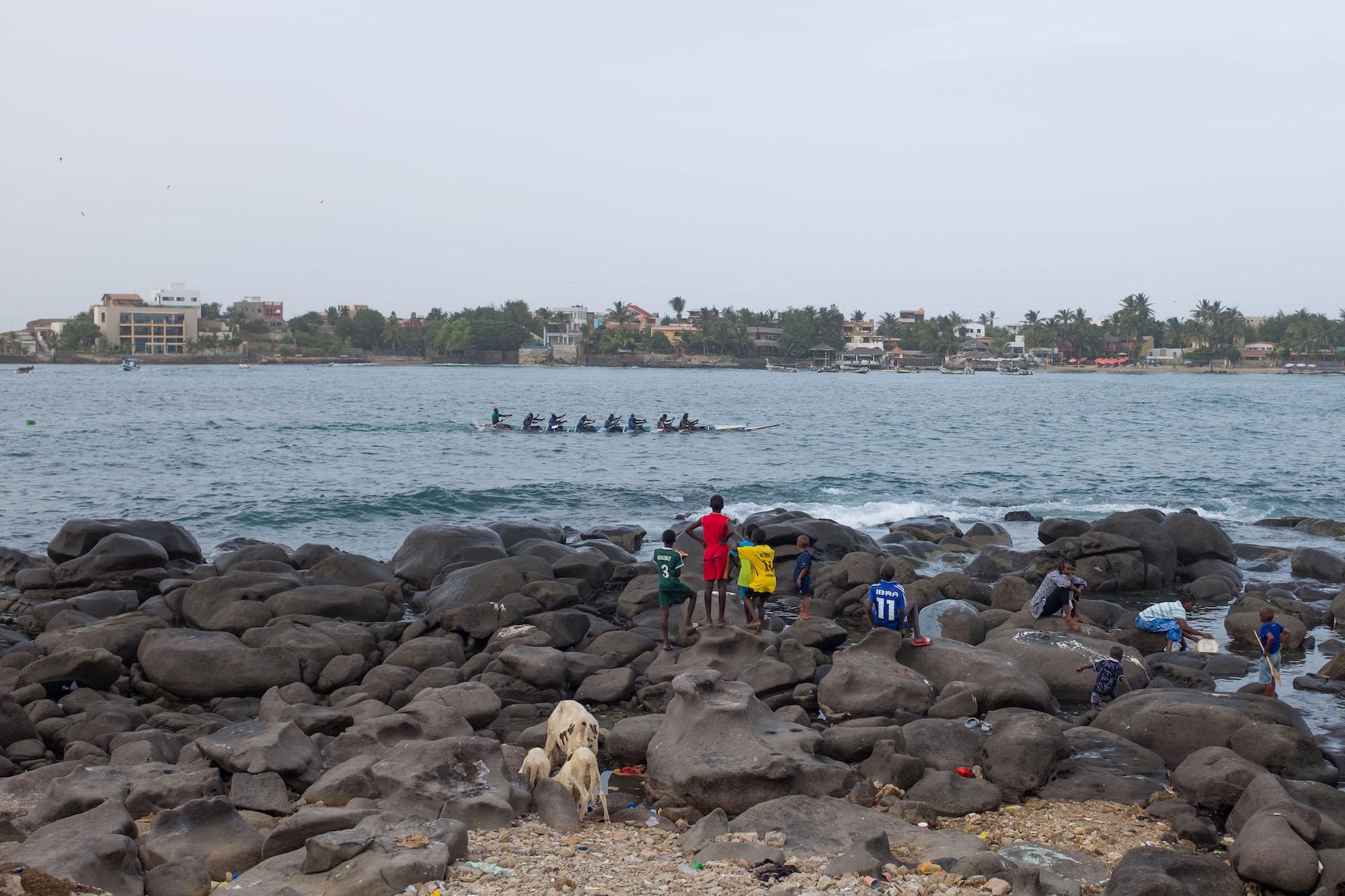 The children of Ngor watch as the village&#39;s rowing team trains in the waters between the...