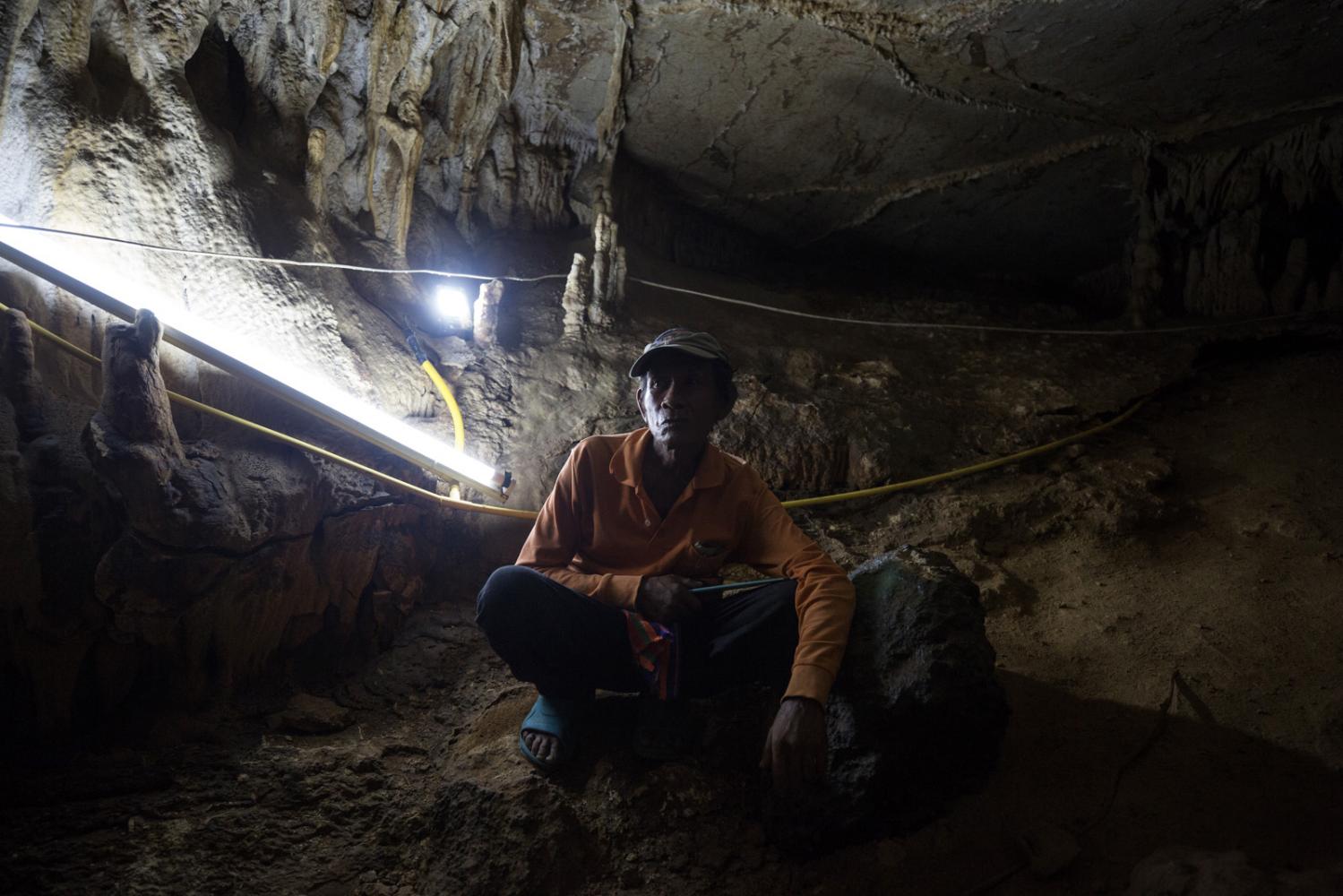 Kiang Pimpan, 57, sits inside a large cave complex containing 10 chambers in an adjacent mountain. The locals fear that when the mining company uses dynamite to explode the rock it could cause the collapse of this cave that they hope will attract tourists in the future