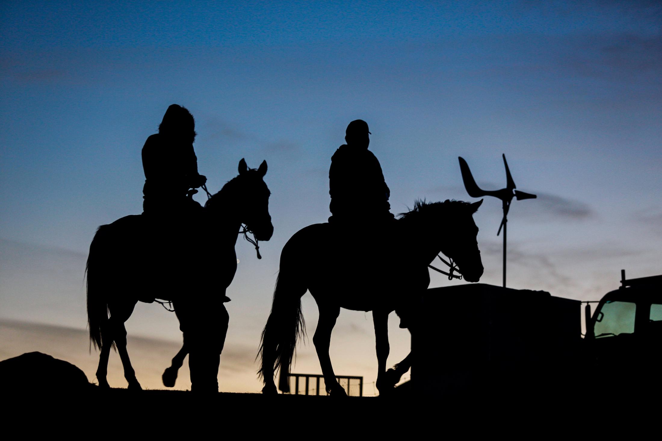 Decolonizing Water - Two young men ride on horseback around the Sacred Stone...