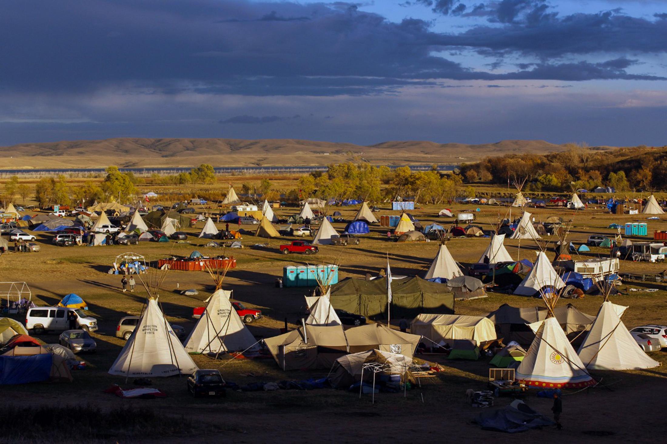 Decolonizing Water - The sunset glistens on tipis at the Sacred Stone Camp in...