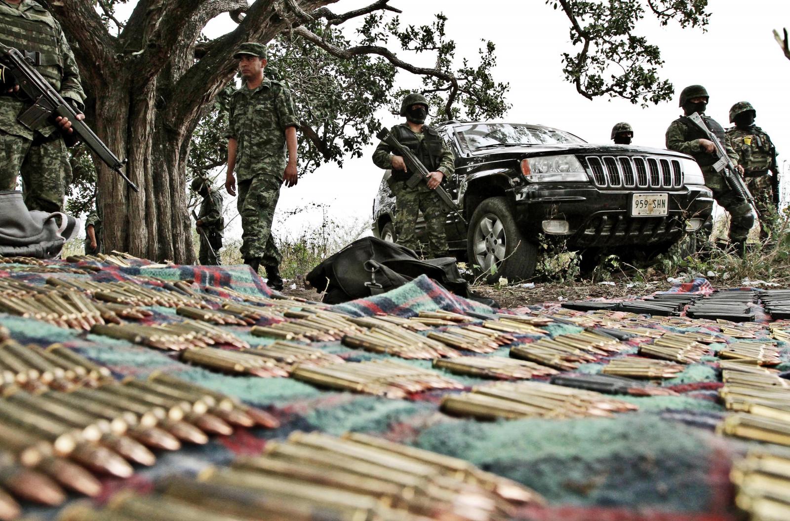 Mexican Army soldiers stand guard behind forfeiture of guns, drugs and two trucks to alleged members of drug cartels in the community Paso de Ovejas Veracruz, and presented to the press on March 05, 2012. Mexican army is carrying out the military operation &quot;Veracruz Safe&quot; with support of marines and federal policemen in the state of Veracruz. AFP PHOTO/Lucas CASTRO