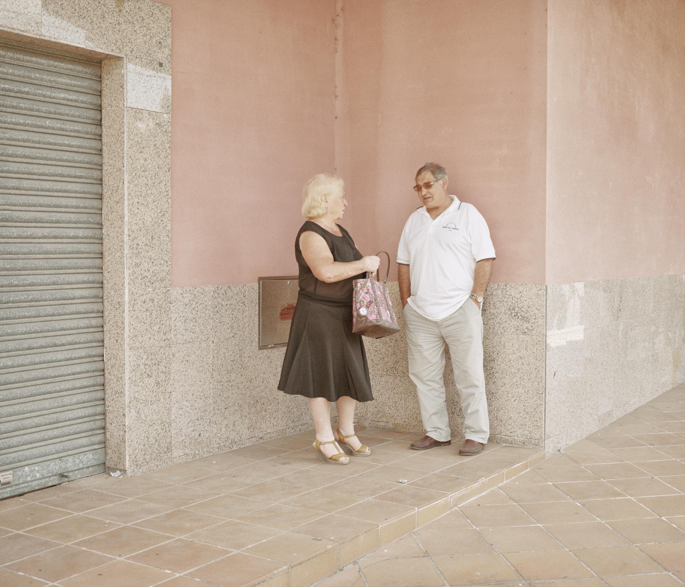 Just a Line - Spain, Goian. A local couple stand in front of a closed...