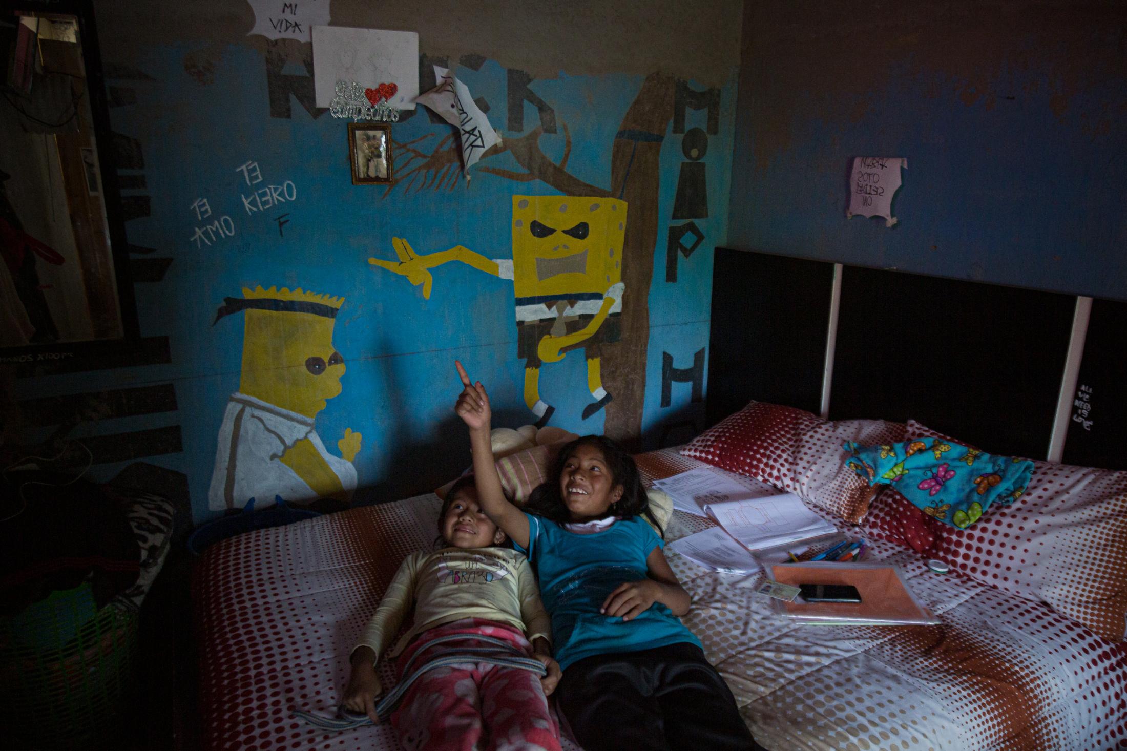 Anal&iacute; Caiza (6) accompanies her cousin, Celina Paucar (12), at her grandmother&#39;s house after she does her homework. They watch TV and play in their aunt and uncle&#39;s room when Celina finishes the homework that her school sends her through Whatsapp, on the afternoon of May 22, 2020. Cotogchoa-Ecuador. Andr&eacute;s Y&eacute;pez. 