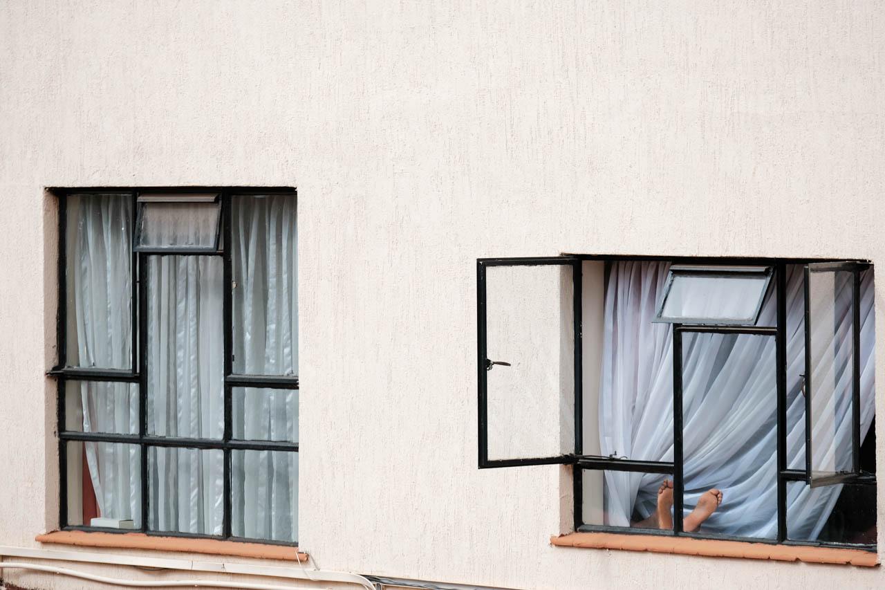 Kabir Dhanji | COVID-19 Quarantine Nairobi - A man puts his feet in the window to enjoy the afternoon...