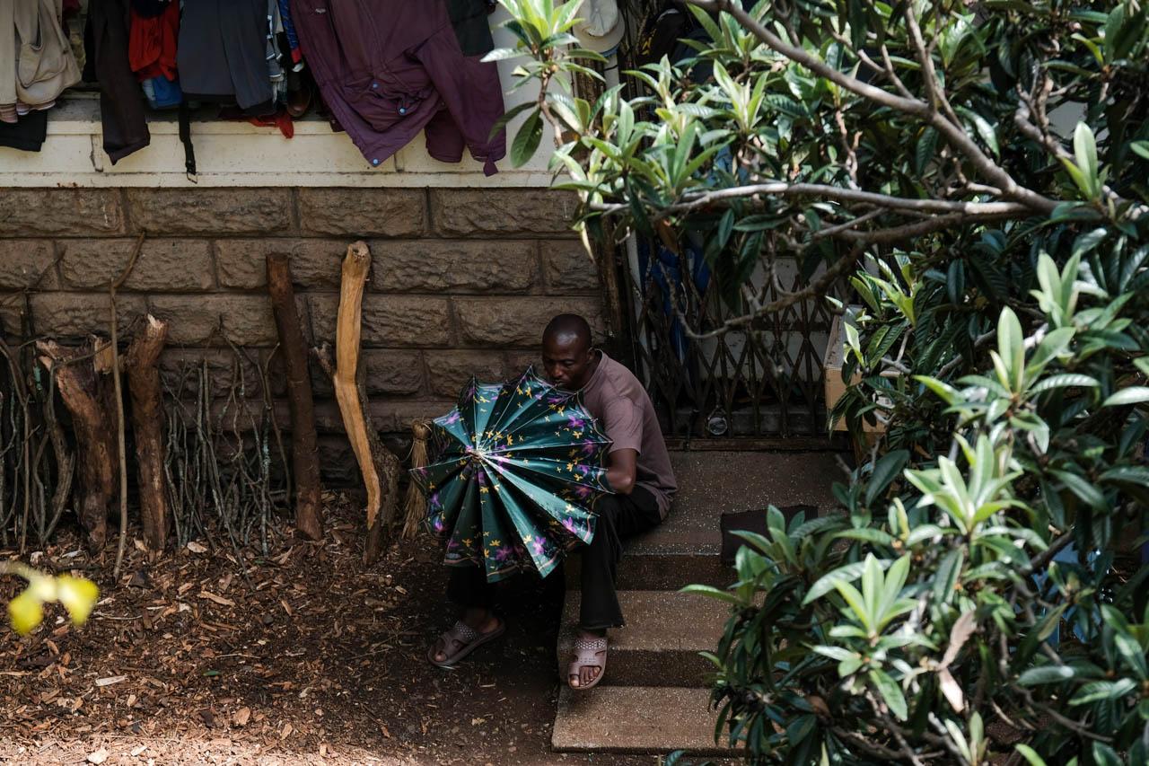 Kabir Dhanji | COVID-19 Quarantine Nairobi - A man plays with his umbrella at property neighbouring a...