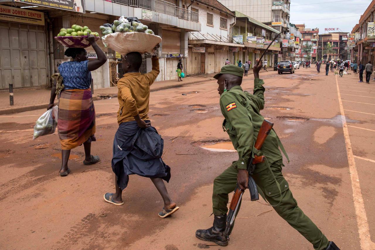 A police officer beats vendors found working on the streets of Kampala in contravention of a presidential directive which required all citizens to stay home.