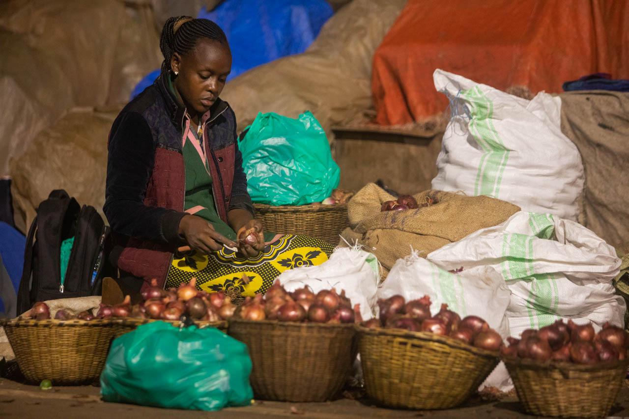 A vendor cleans onions at night at a market.