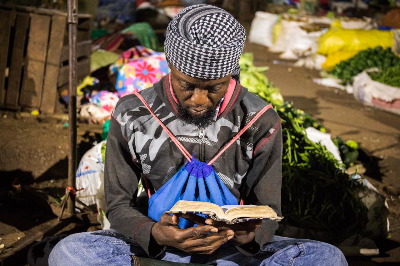 A trader recites the Quran next to his stock.