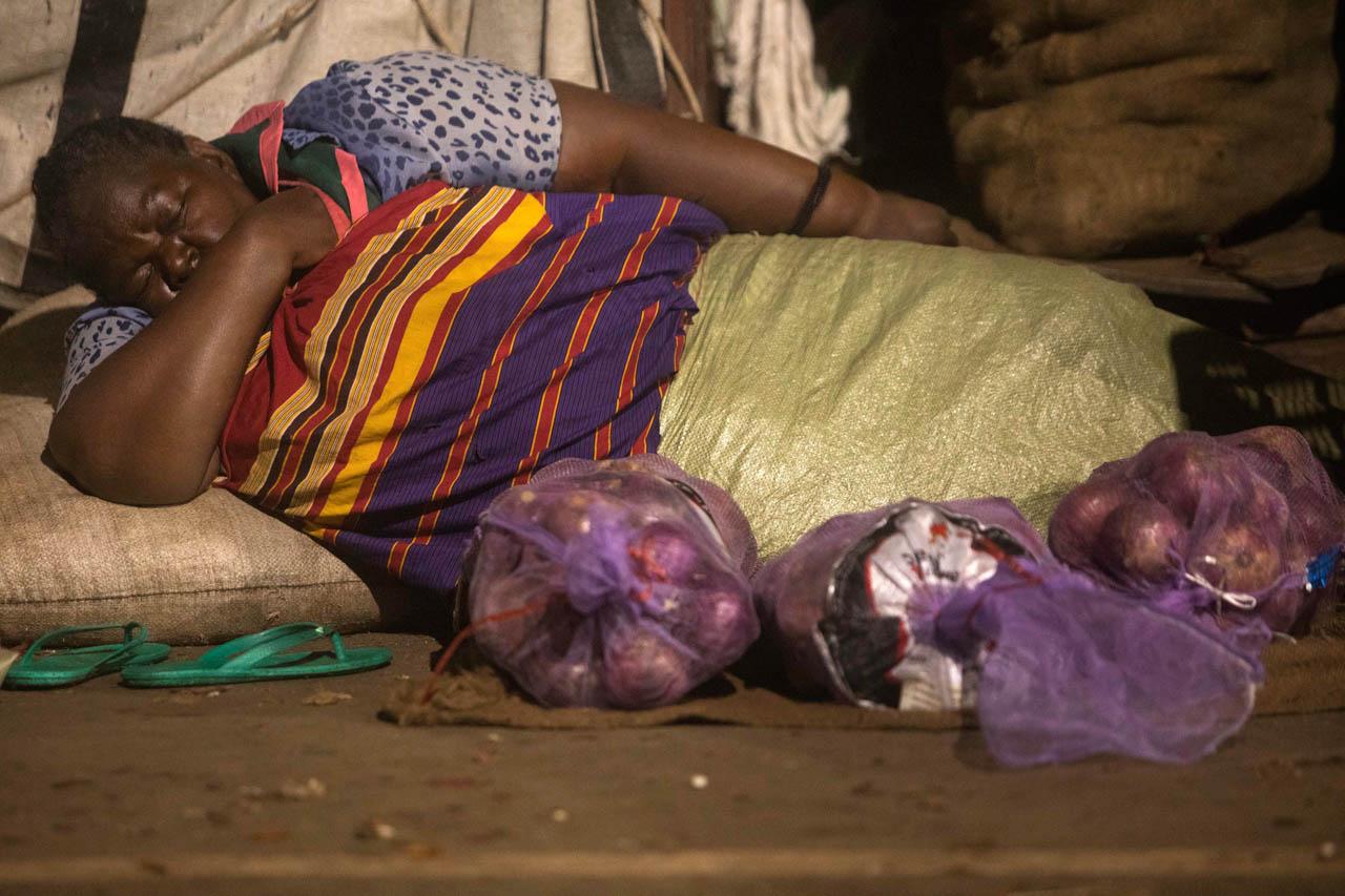 An old vendor sleeps next to her commodities at Nakasero market