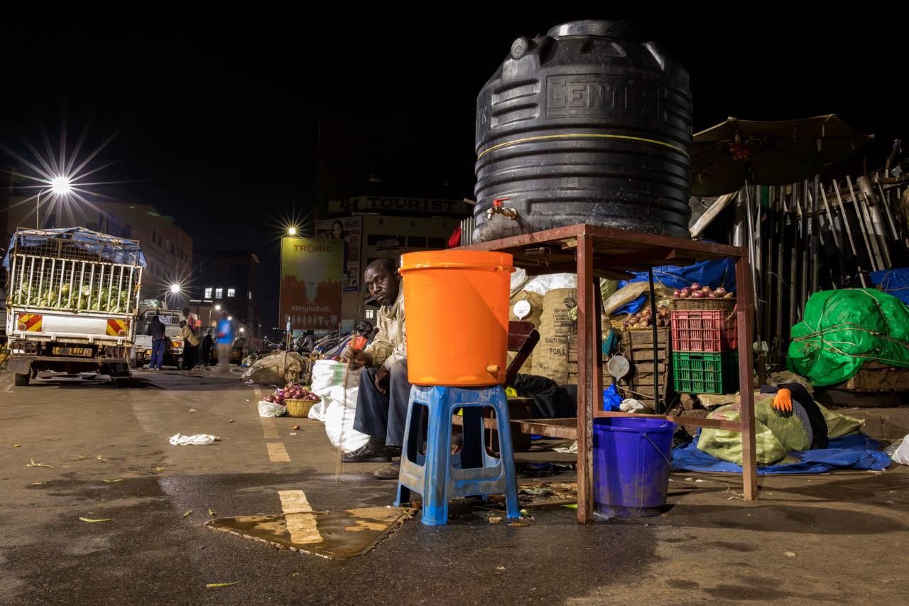 A security guard watches over at the entrance of Nakasero market as traders sleep inside.