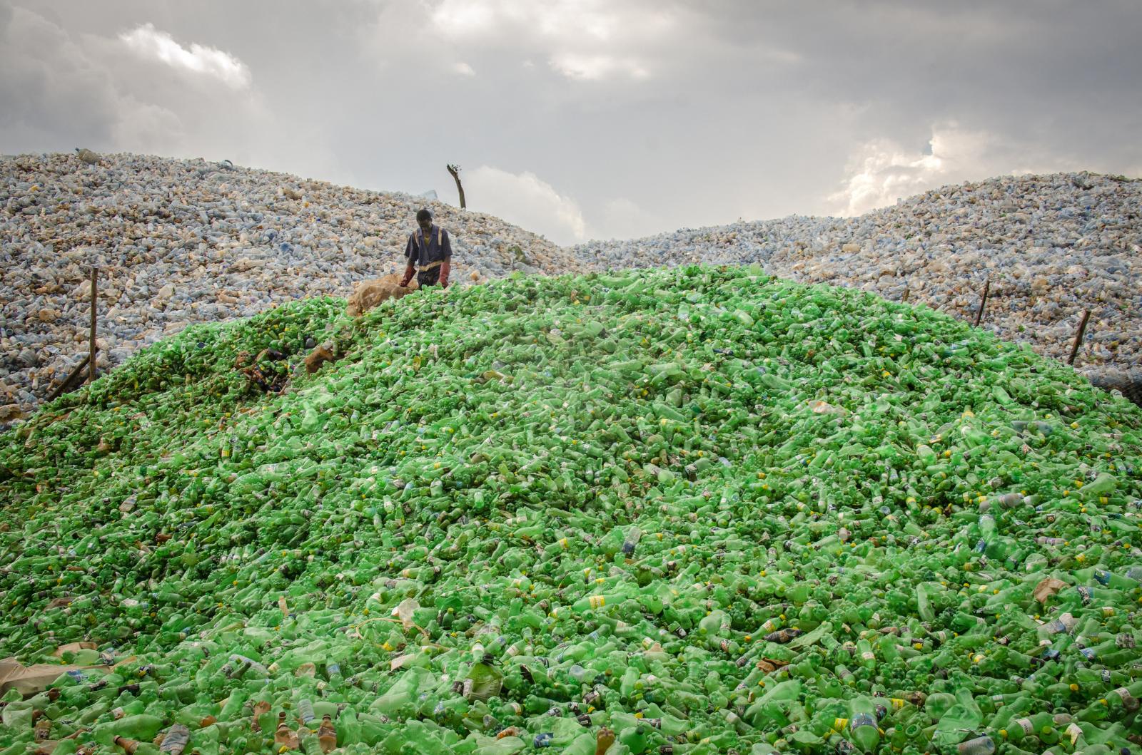 19-year old Egunyu Mark sorts through a mound of plastic bottles as he prepares them for recycling. Thousands of tonnes of waste are collecting at sites like this one in Bweyogerere, because the industry is over capacity. The recycling of plastics has greatly reduced the amount of plastics in the city though, particularly in its water channels.