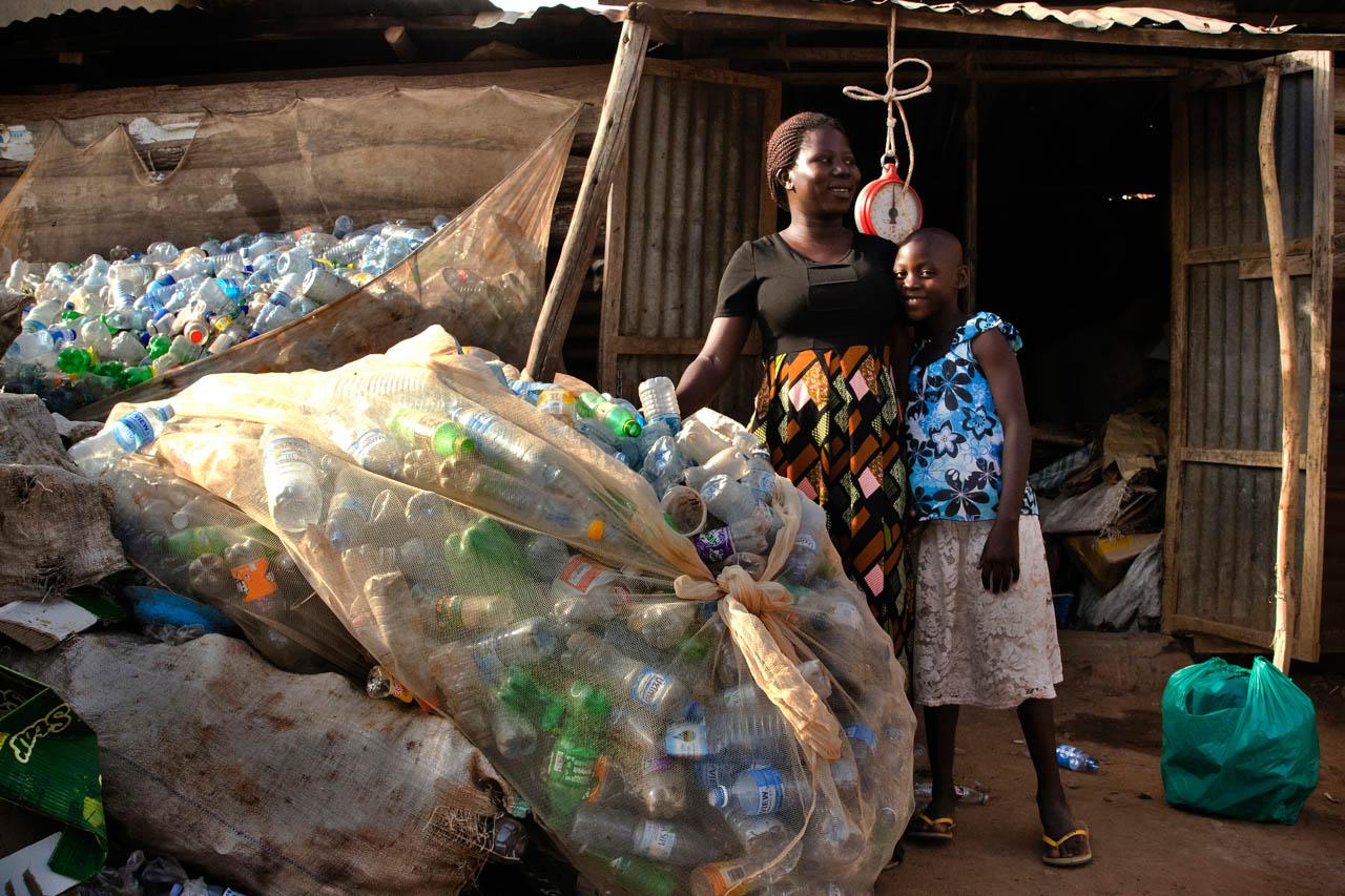 Mariam Nnakanwagi and her daughter pose for a portrait in front of their business. Ms. Nnakanwagi, a single mother of four, supports her children by collecting and selling plastics for recycling.   