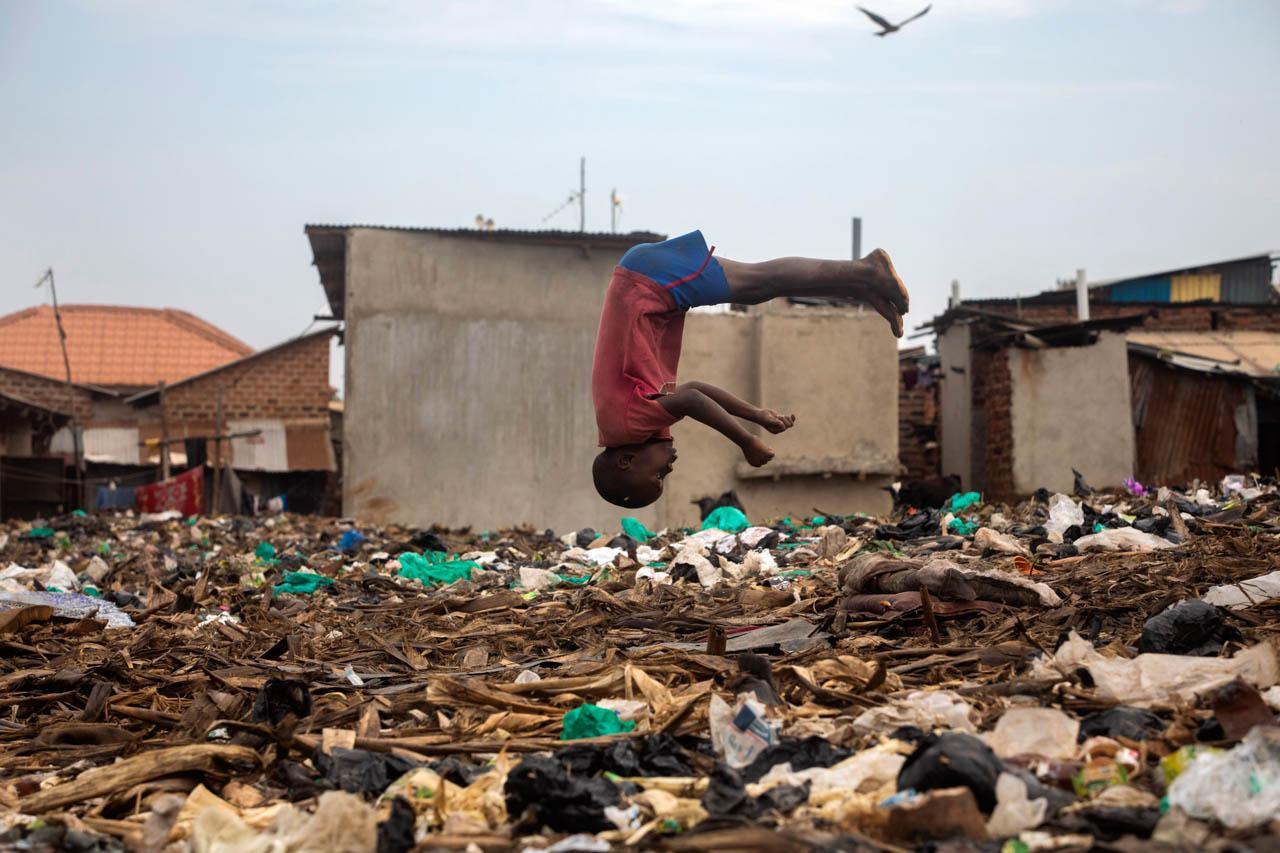 A little boy plays on a garbage pile in Nsambya, Kampala. The children like to practice their gymnastics on the garbage pile because it offers a soft landing.