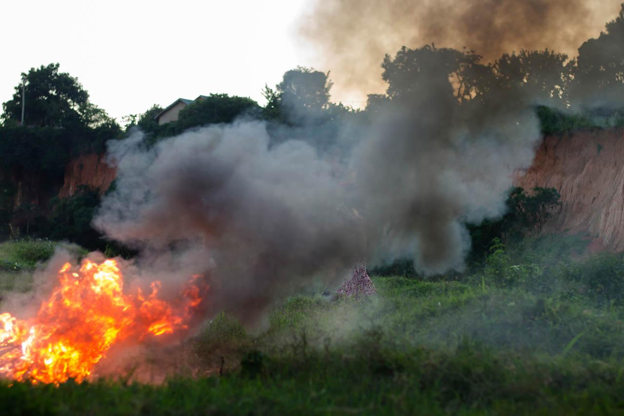 A pregnant woman walks through smoke from a heap of burning plastic in Kampala. The chemicals in this smoke are very harmful to human health.